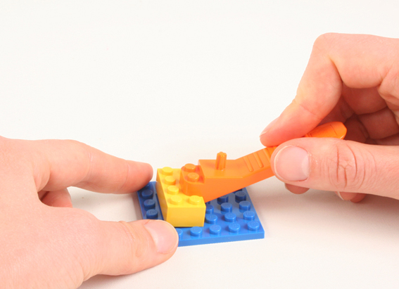 lego brick separator being used to separate a yellow brick from a blue lego plate